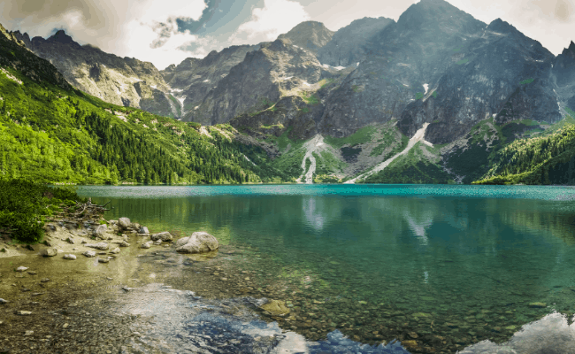 Tree-covered mountains behind a bright teal lake.