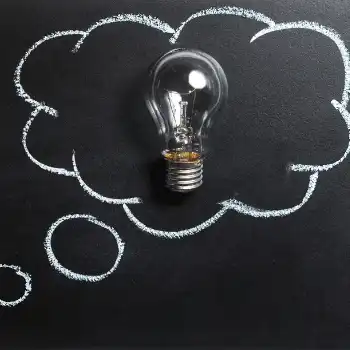 Thought bubbles drawn on a chalkboard with a lightbulb inside the biggest one.