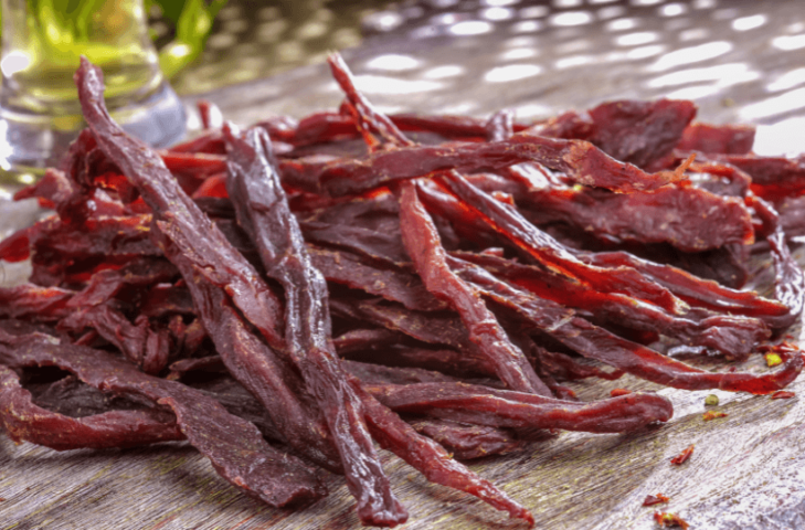 A large pile of homemade beef jerky on a table.