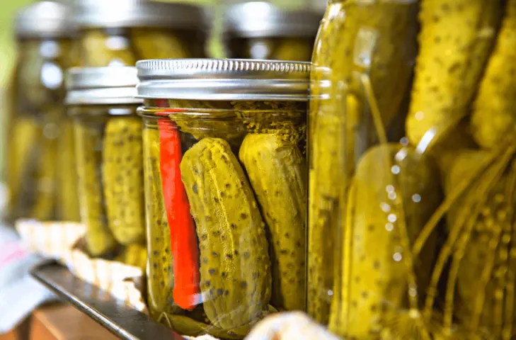 Several close up mason jars full of pickles.