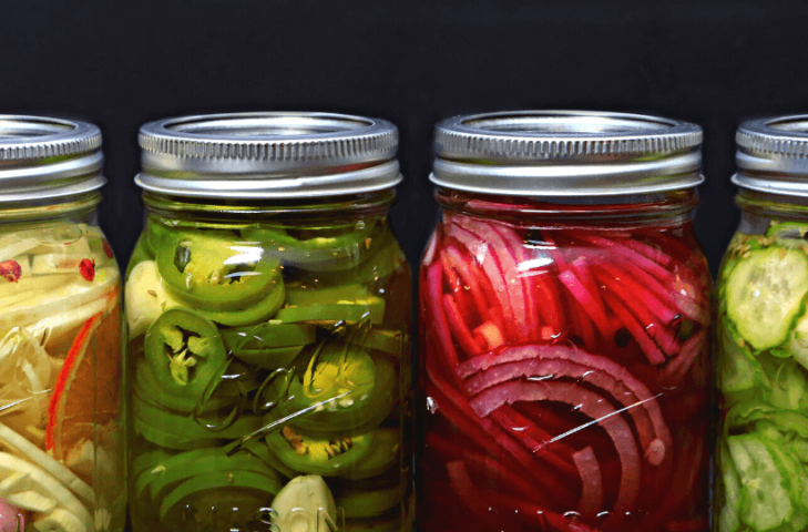 Mason jars full of pickled jalapenos, red onions, and cucumbers.
