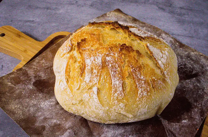 A whole loaf of homemade bread sitting on a cutting board.